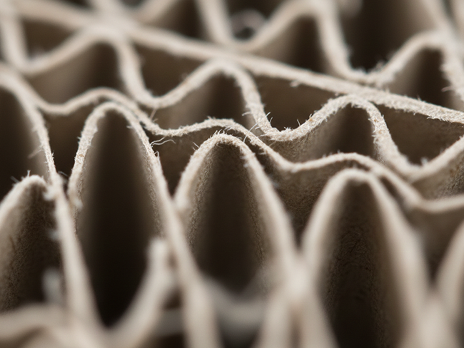 Extreme close-up of wavy corrugated paper fluting layers.